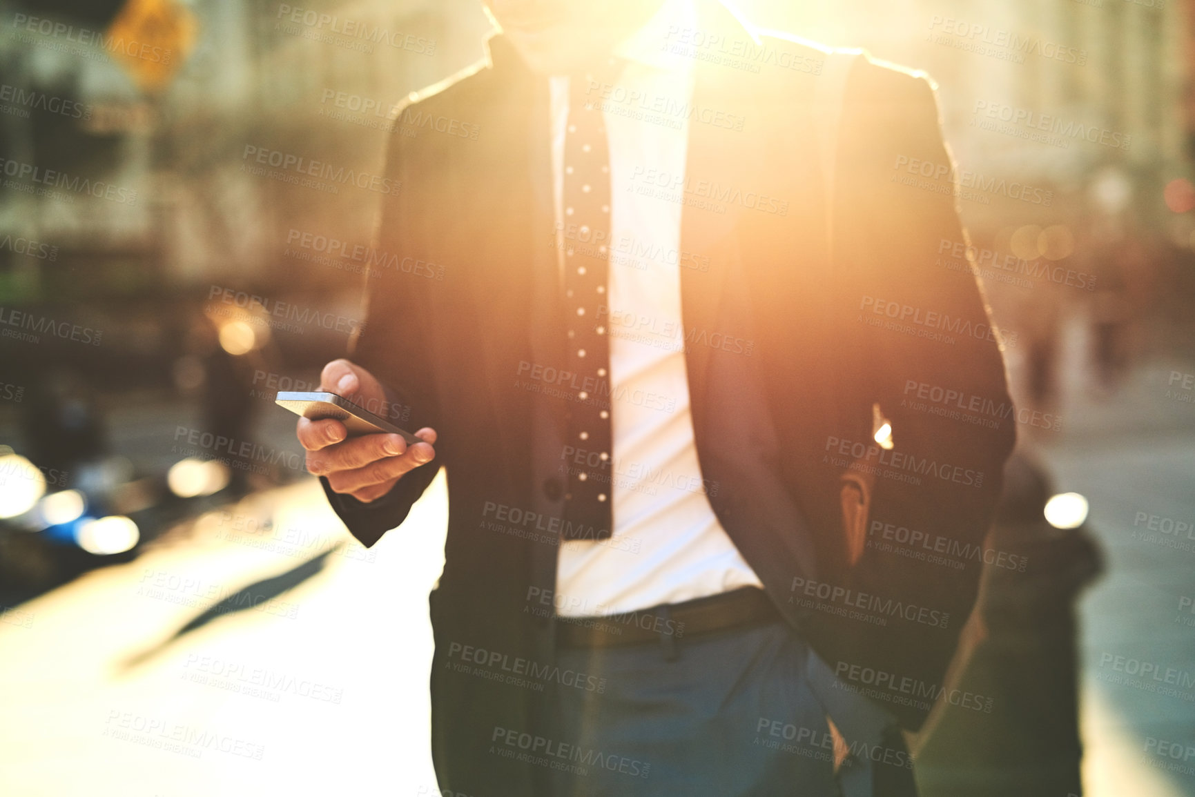 Buy stock photo Shot of an unrecognizable man texting on his cellphone while walking the busy streets of the city in the morning