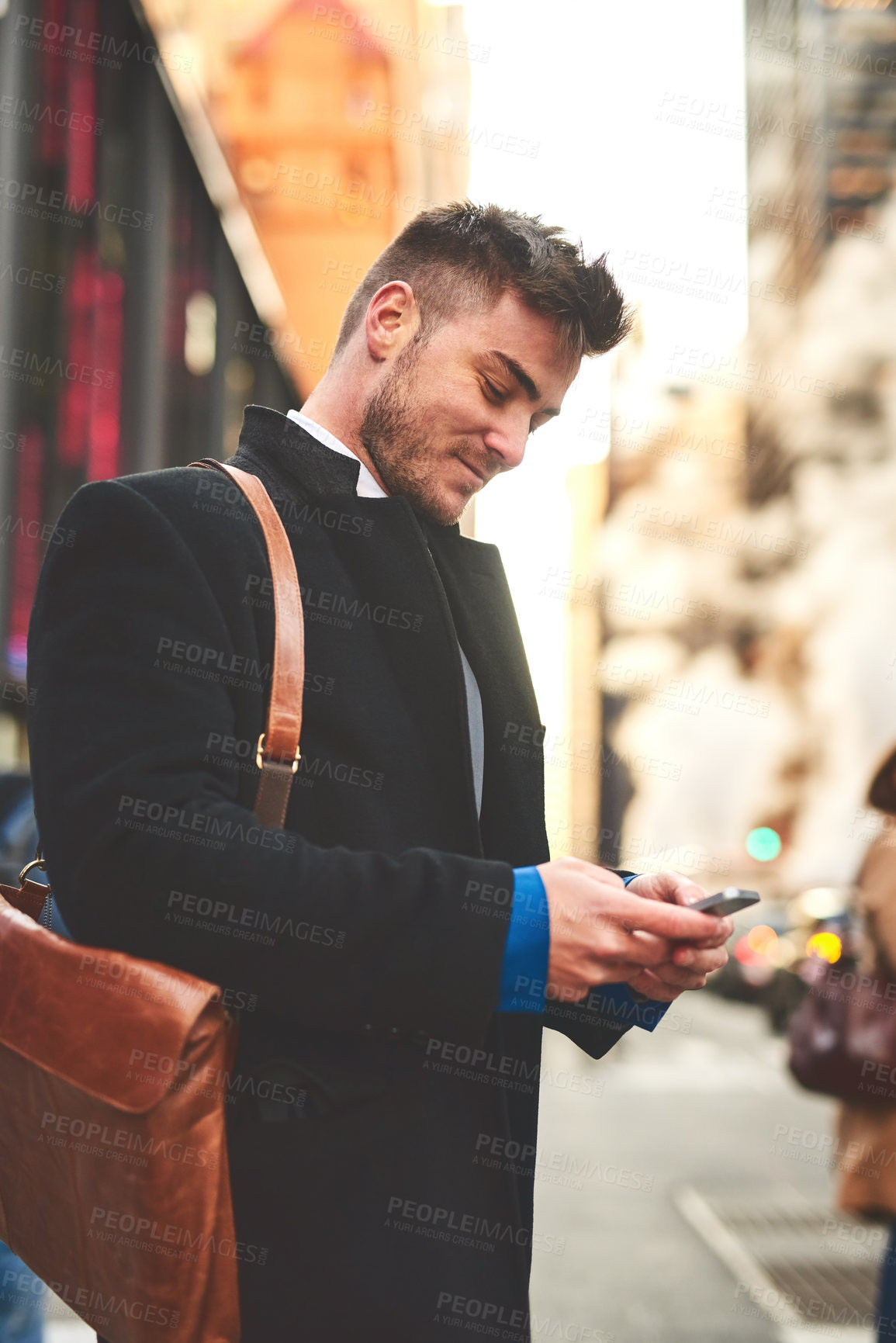 Buy stock photo Shot of a young well dressed man texting on his cellphone while waiting for a taxi to get him to work in the morning