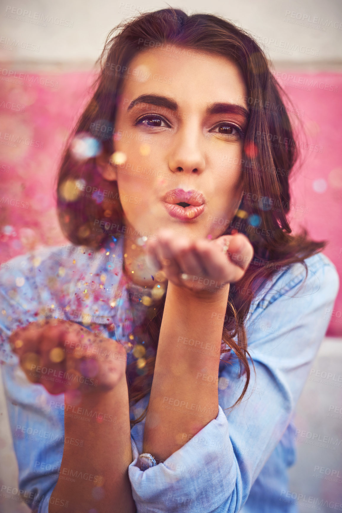 Buy stock photo Portrait of a beautiful young woman blowing confetti outside