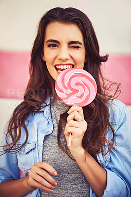 Buy stock photo Portrait of a beautiful young woman holding candy against a wall outside