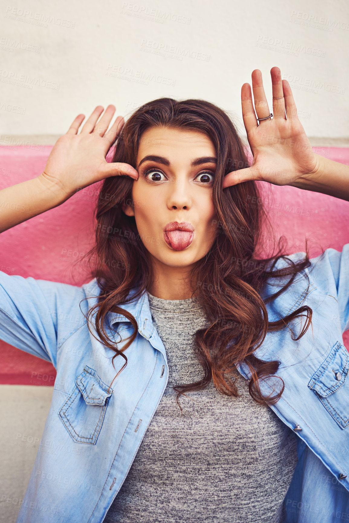 Buy stock photo Bunny ears, tongue out and portrait of woman on wall background outdoor for playful expression. Comic, funny face and joyful with happy model person in denim jacket for comedy or silly humor