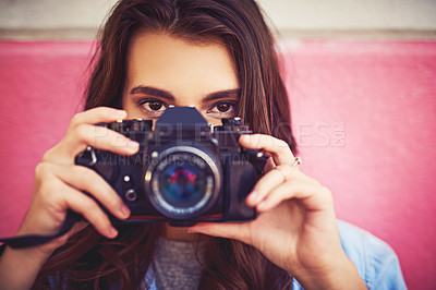 Buy stock photo Portrait of a beautiful young woman holding a dslr camera and posing against a wall outside