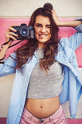 Buy stock photo Portrait of a beautiful young woman holding a dslr camera and posing against a wall outside