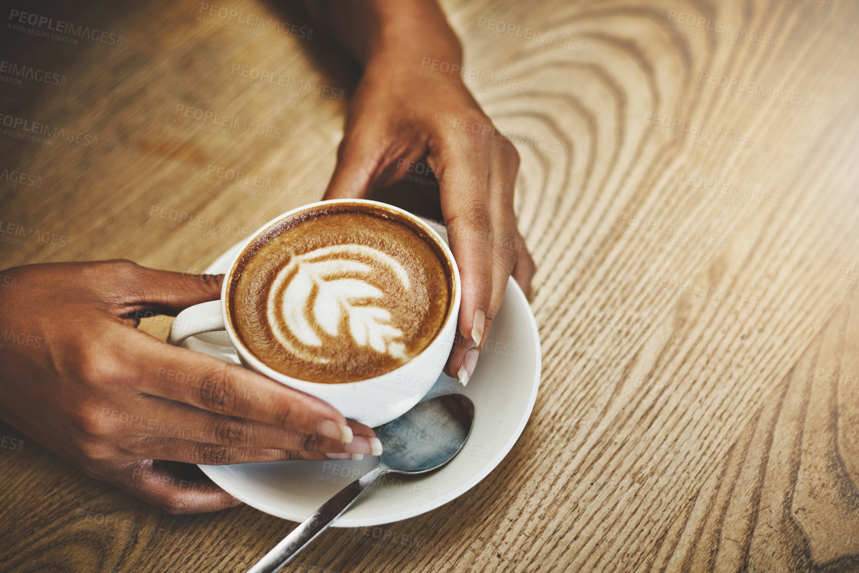 Buy stock photo High angle shot of an unrecognizable woman holding a cup of coffee decorated with froth art