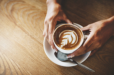 Buy stock photo High angle shot of an unrecognizable woman holding a cup of coffee decorated with froth art