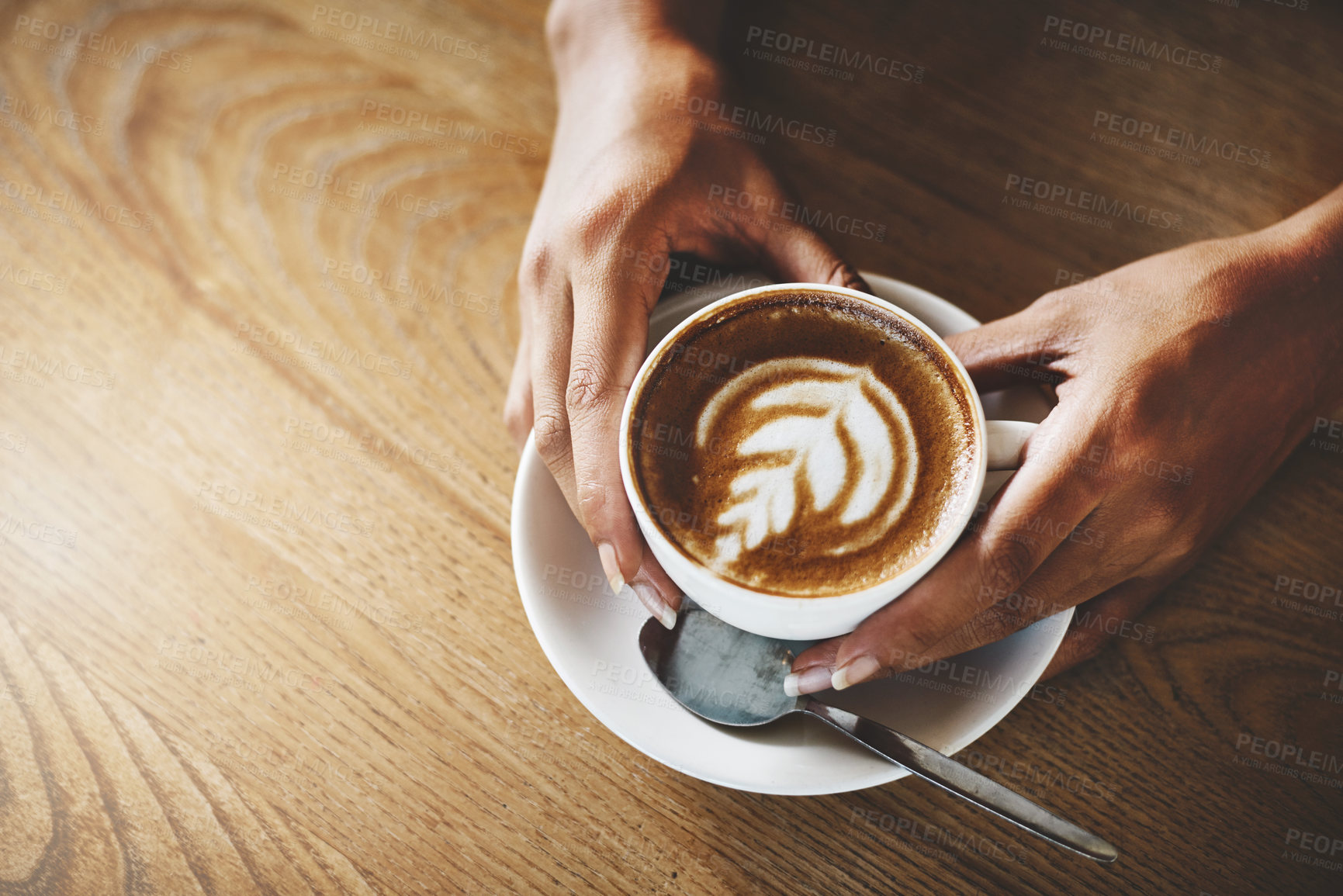 Buy stock photo High angle shot of an unrecognizable woman holding a cup of coffee decorated with froth art