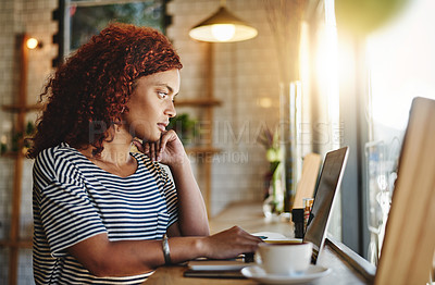 Buy stock photo Shot of an attractive young woman working on a laptop in a cafe