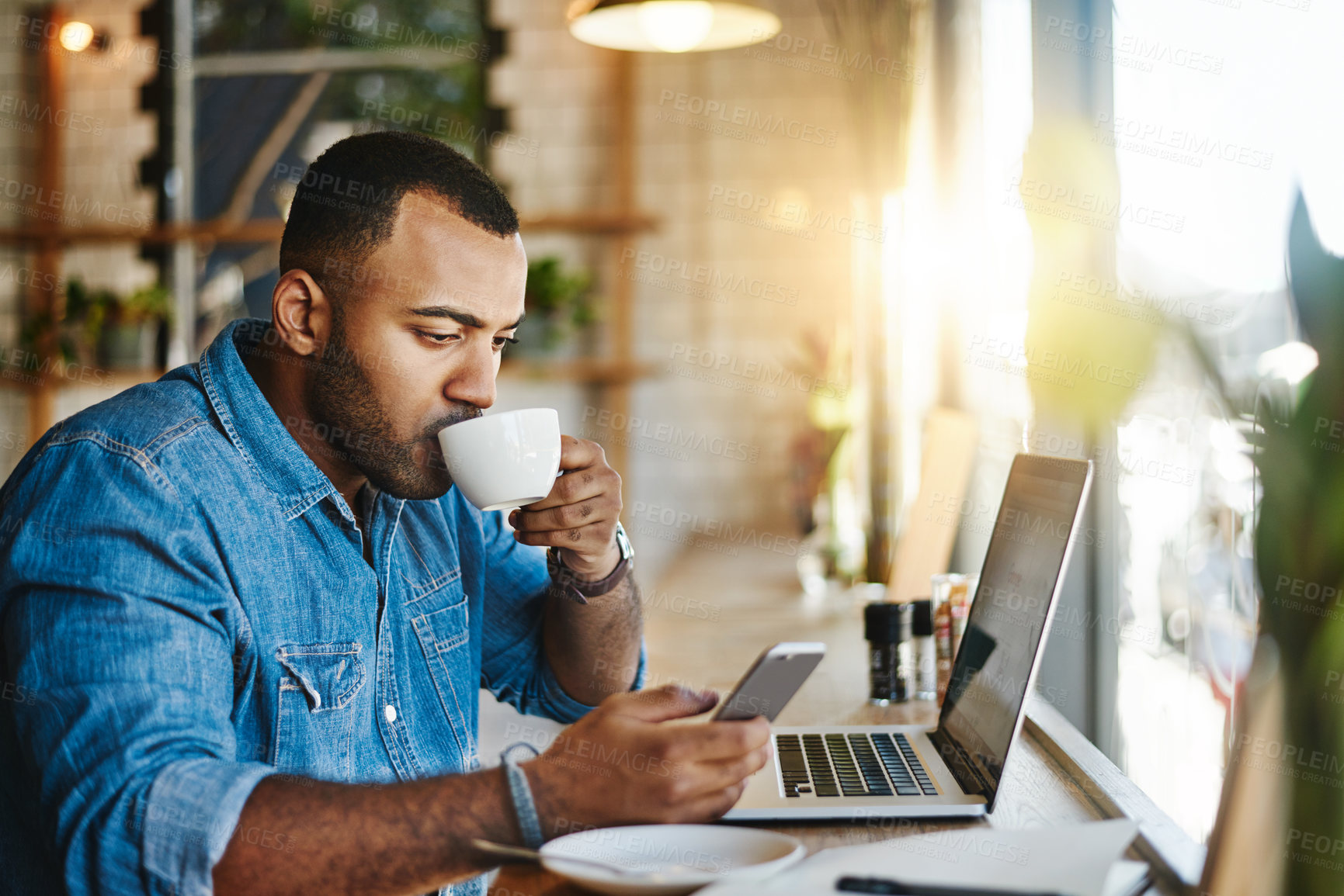 Buy stock photo Shot of a handsome young man drinking coffee while working working in a cafe