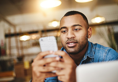 Buy stock photo Shot of a handsome young man using a cellphone in a cafe