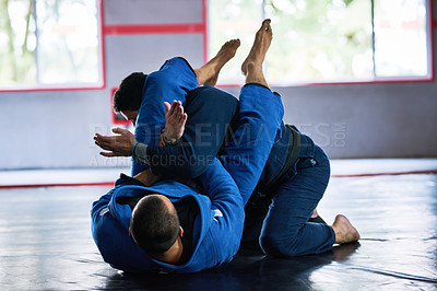 Buy stock photo Full length shot of two young male athletes sparring on the floor of their dojo