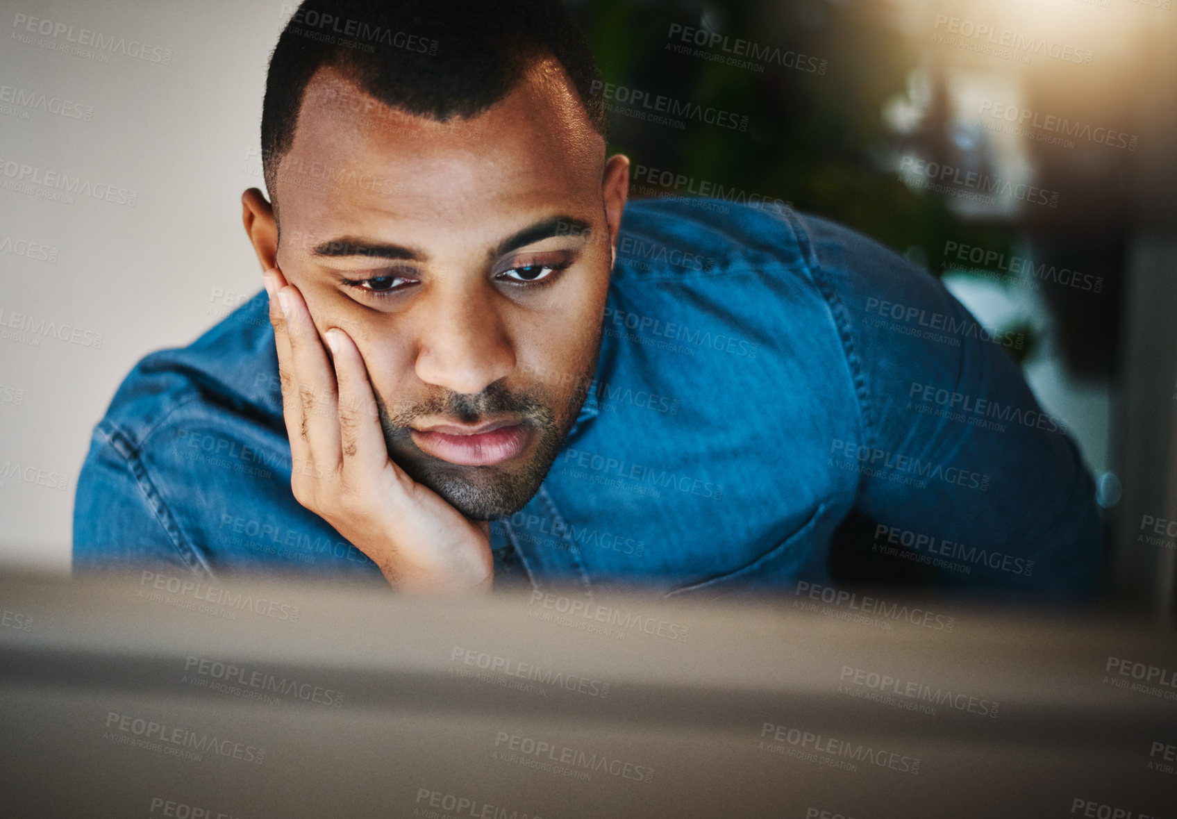 Buy stock photo Shot of a young businessman looking bored while working during a late night in a modern office