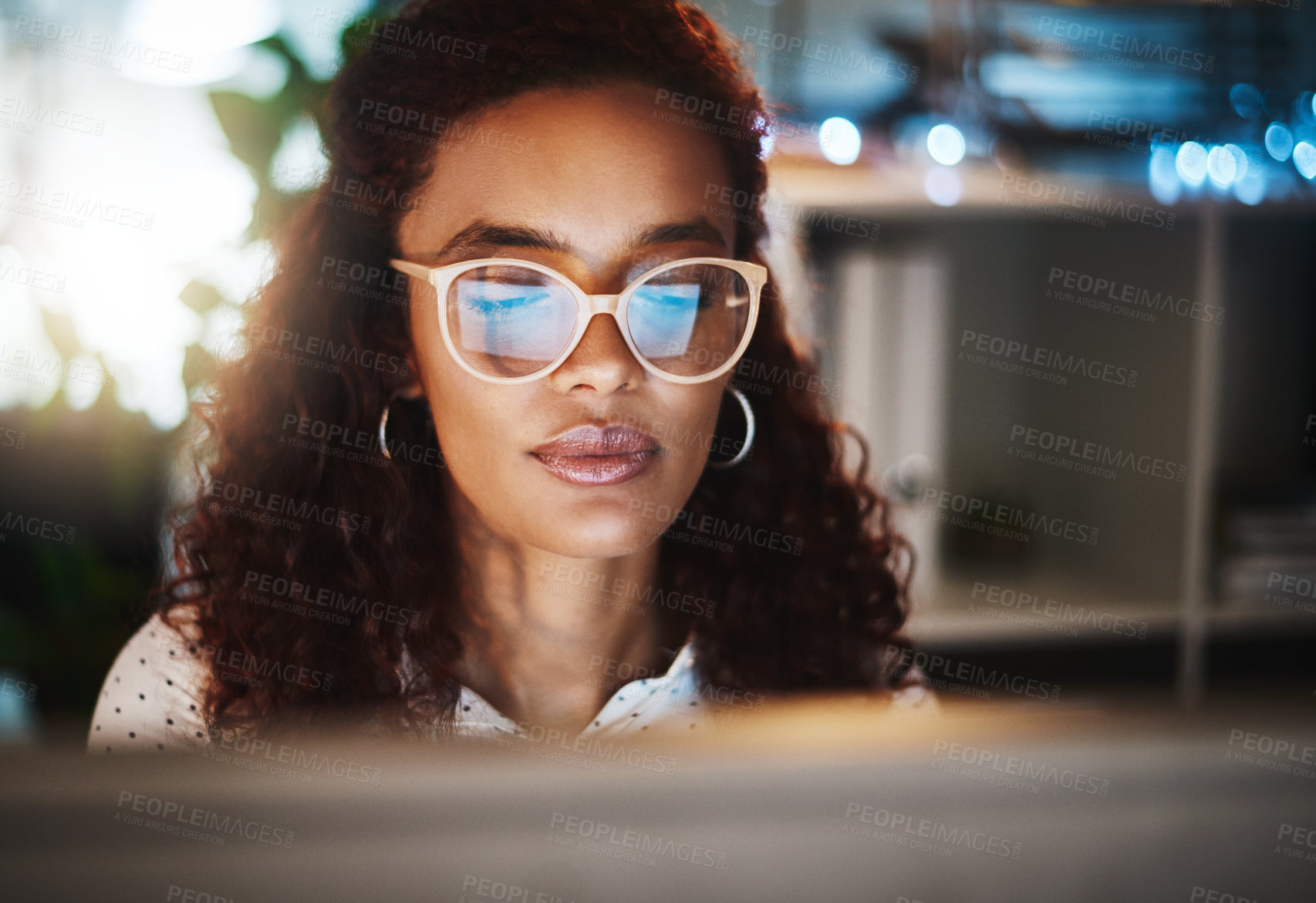 Buy stock photo Shot of a young businesswoman using a computer during a late night at work in a modern office