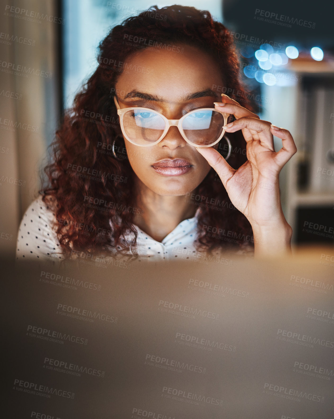 Buy stock photo Shot of a young businesswoman using a computer during a late night at work in a modern office