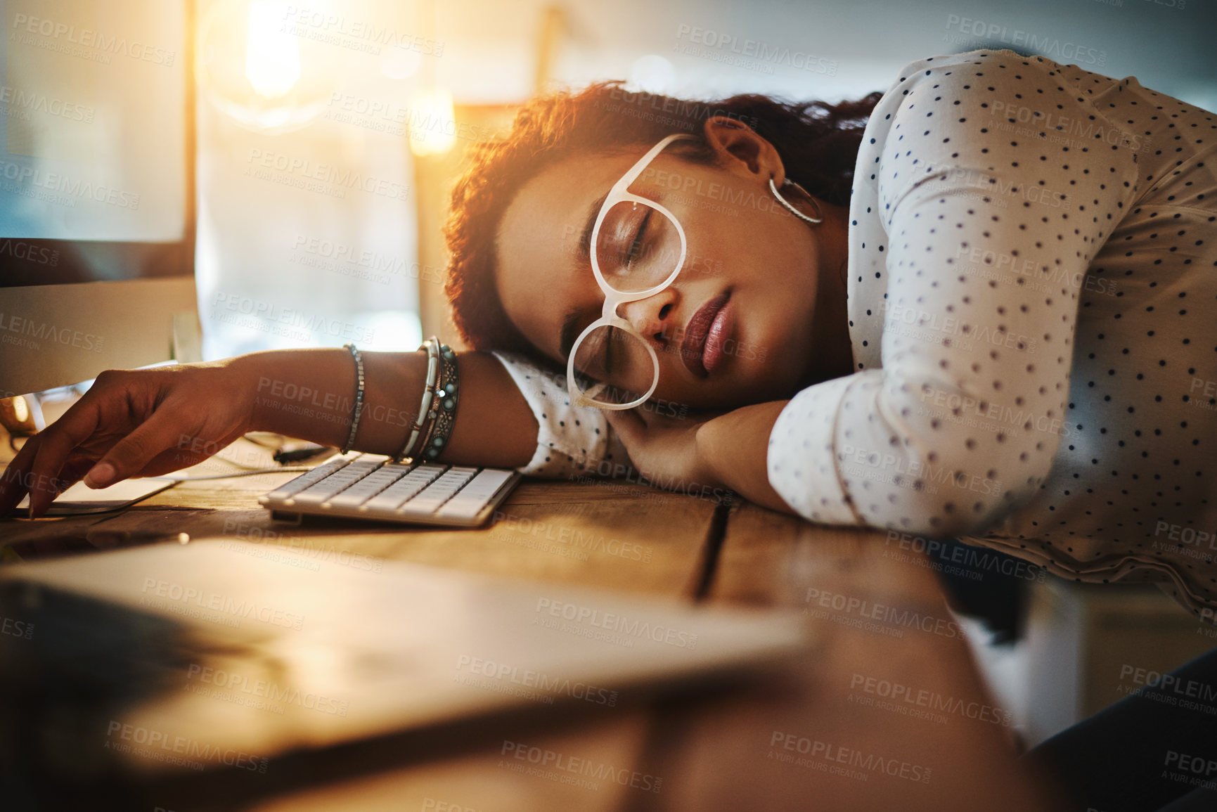 Buy stock photo Shot of an exhausted young businesswoman sleeping at her desk in a modern office
