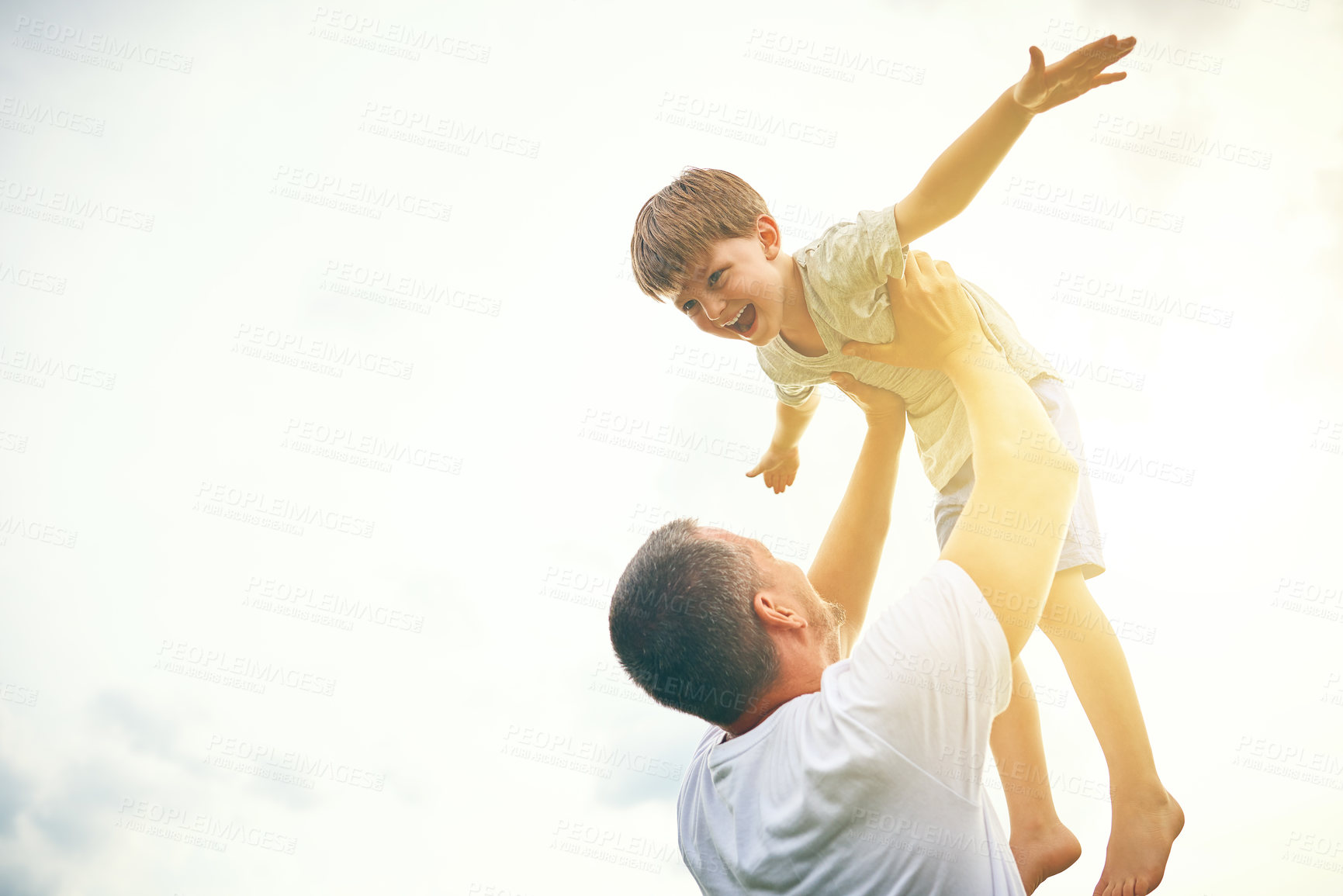 Buy stock photo Cropped shot of a father tossing his adorable son into the air outside