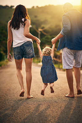 Buy stock photo Rearview shot of an unrecognizable family taking a walk down the road outside