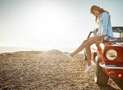 Buy stock photo Shot of a beautiful young woman relaxing on the hood of her car on a road trip