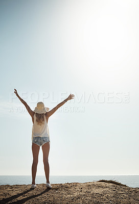 Buy stock photo Rearview shot of an attractive young woman enjoying her day on the beach