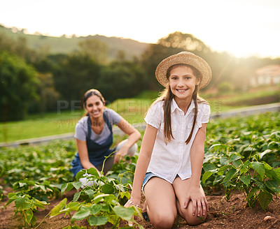 Buy stock photo Portrait of a young girl working on the family farm with her mother in the background