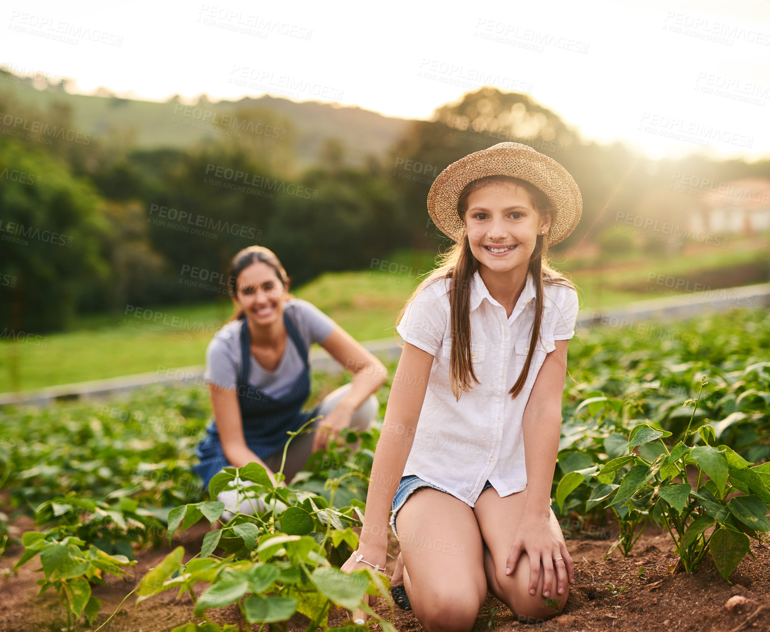 Buy stock photo Portrait of a young girl working on the family farm with her mother in the background