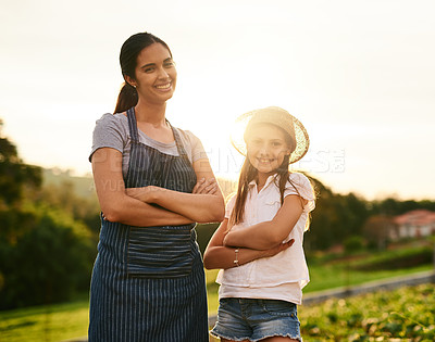 Buy stock photo Cropped portrait of an attractive young woman and her daughter standing with their arms folded on the family farm