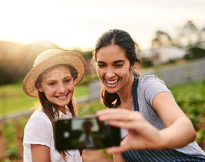 Buy stock photo Cropped shot of an attractive young woman and her daughter taking selfies while working on their family farm
