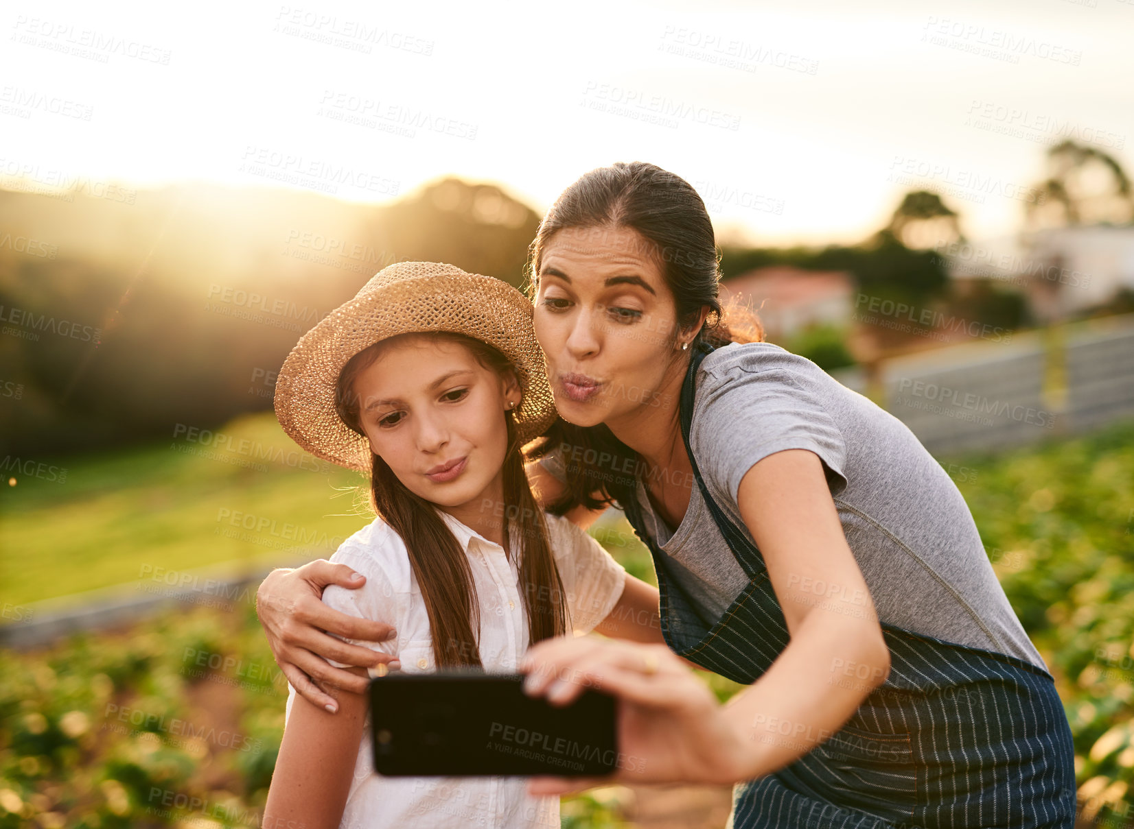 Buy stock photo Cropped shot of an attractive young woman and her daughter taking selfies while working on their family farm