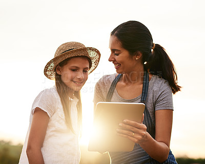Buy stock photo Cropped shot of an attractive young woman using a tablet while working on the family farm with her daughter