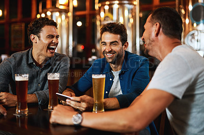 Buy stock photo Shot of a group of young friends seated at a table together while enjoying a beer inside a bar