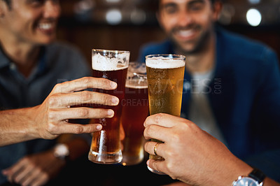 Buy stock photo Closeup of a group of young friends seated at a table together while enjoying a beer and celebrating with a celebratory toast inside a bar