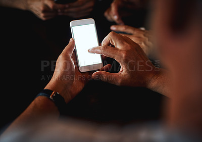 Buy stock photo Closeup of an unrecognizable man texting on his phone while being seated inside of a bar at night