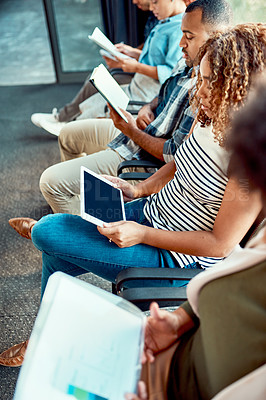 Buy stock photo Shot of a group of young focussed work colleagues seated on chairs next to each other in a row while making notes inside of the office during the day