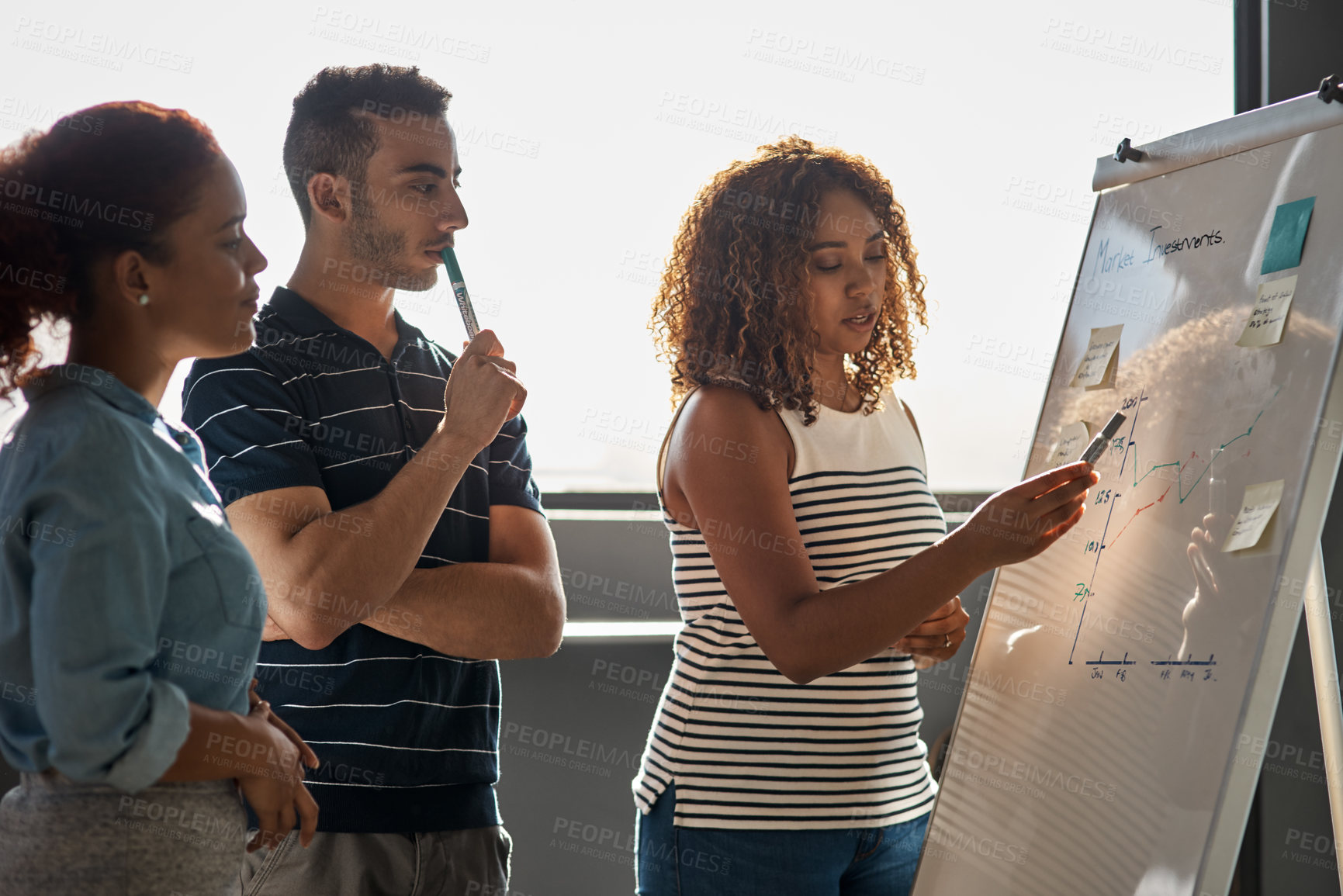 Buy stock photo Shot of a group of young designers brainstorming on a whiteboard in an office