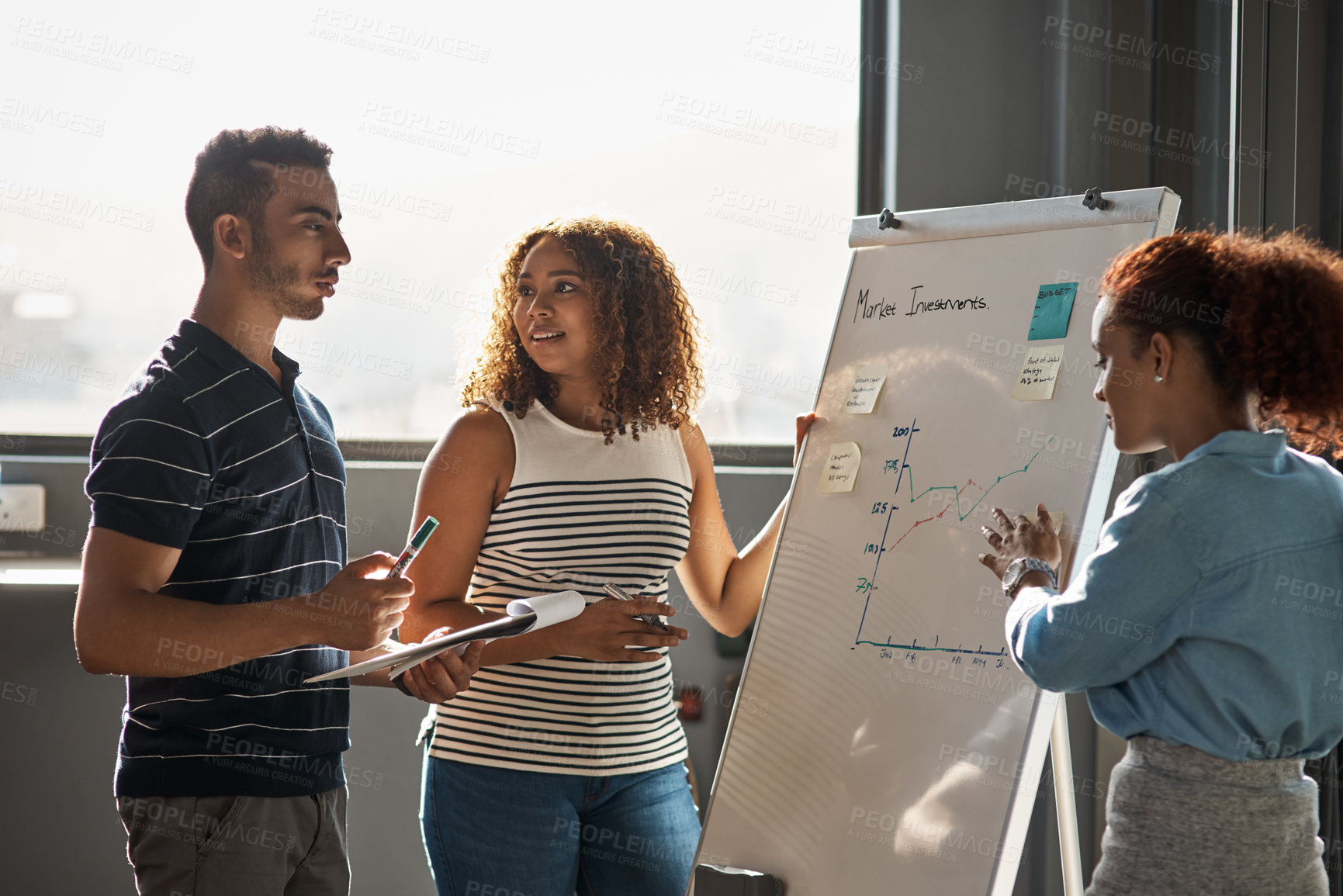 Buy stock photo Shot of a group of young designers brainstorming on a whiteboard in an office