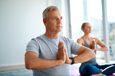 Buy stock photo Cropped shot of a handsome mature man meditating at home with his wife in the background