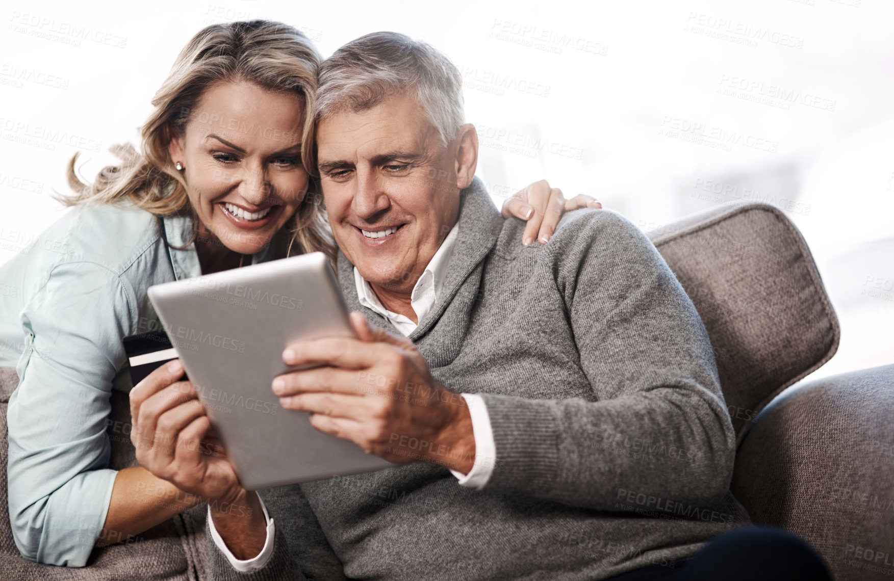 Buy stock photo Shot of a mature couple using a digital tablet and credit card to do online shopping at home