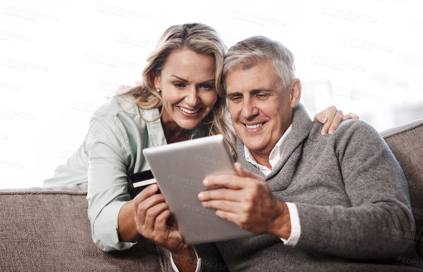 Buy stock photo Shot of a mature couple using a digital tablet and credit card to do online shopping at home