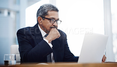 Buy stock photo Shot of a mature businessman working on a laptop in an office
