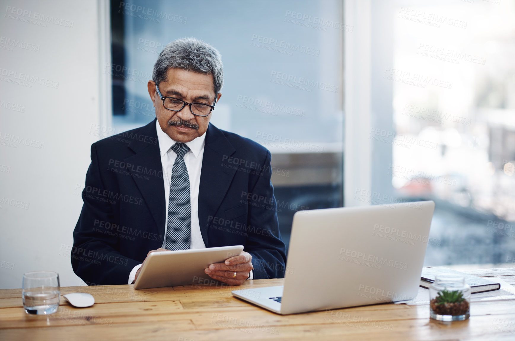 Buy stock photo Shot of a mature businessman working on a digital tablet in an office