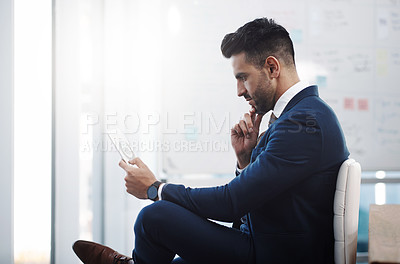 Buy stock photo Shot of a young businessman working on a digital tablet in an office