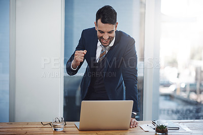 Buy stock photo Shot of a young businessman celebrating while working on a laptop in an office