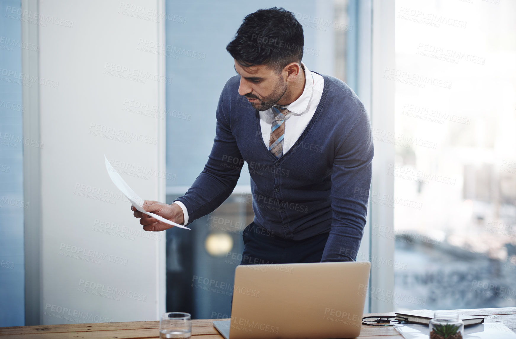 Buy stock photo Shot of a young businessman working on a laptop in an office