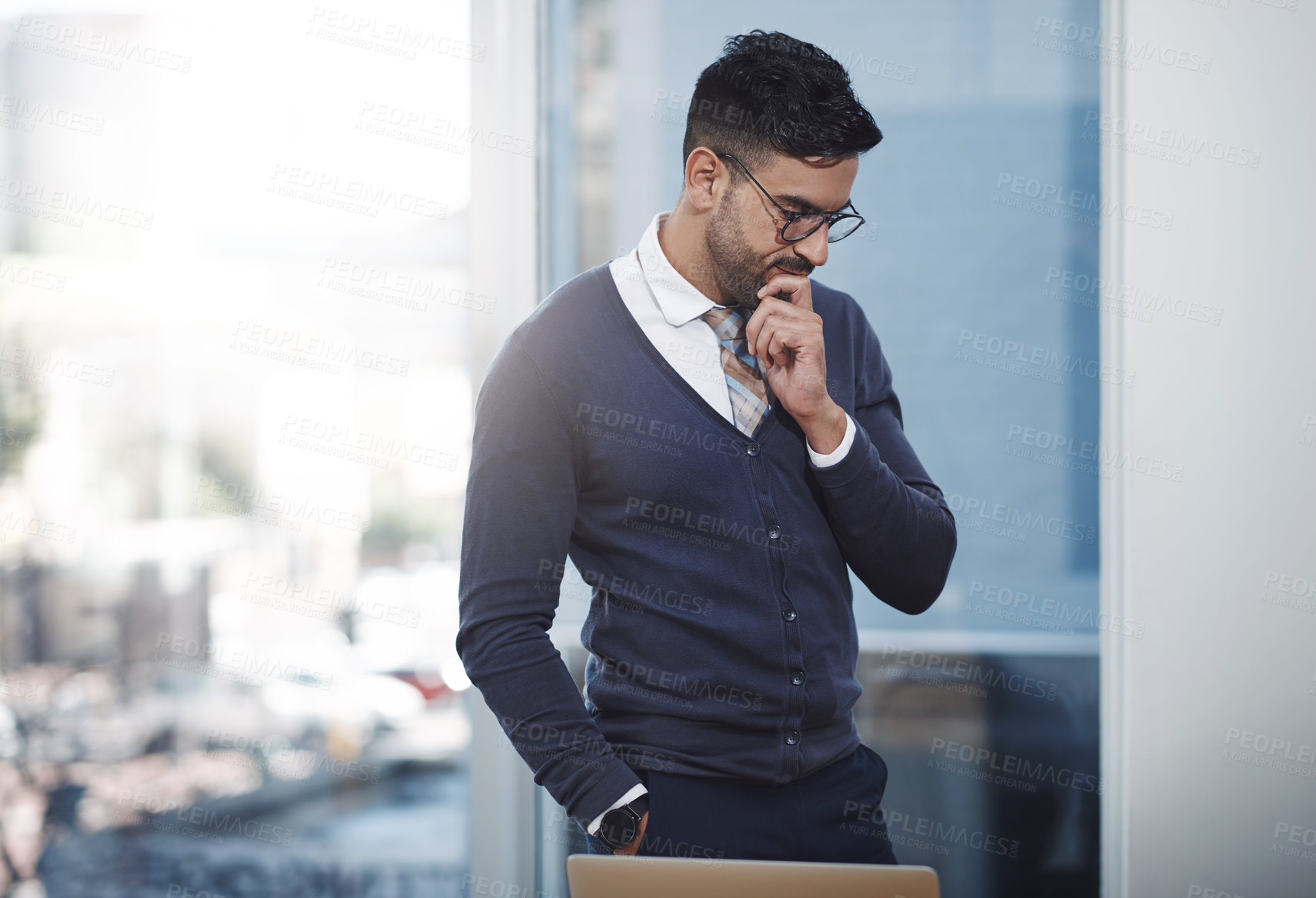 Buy stock photo Shot of a young businessman looking thoughtful in an office