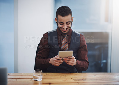 Buy stock photo Shot of a young businessman working on a digital tablet in an office