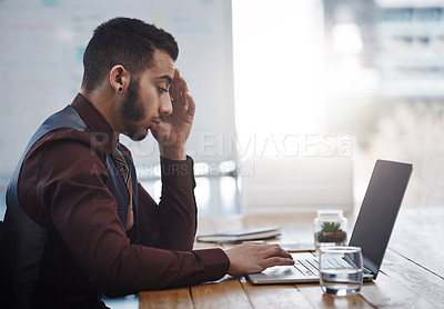 Buy stock photo Shot of a young businessman looking stressed out while working in an office