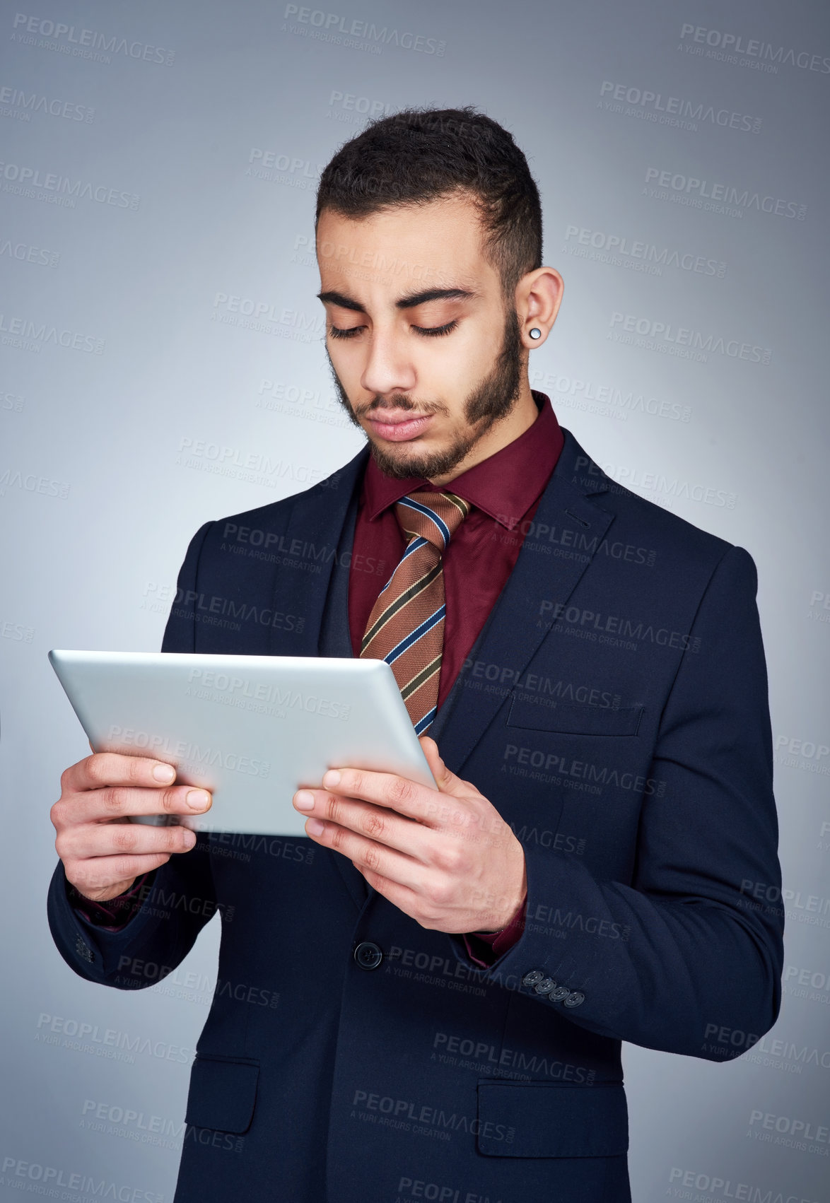 Buy stock photo Studio shot of a handsome young businessman using a tablet against a grey background