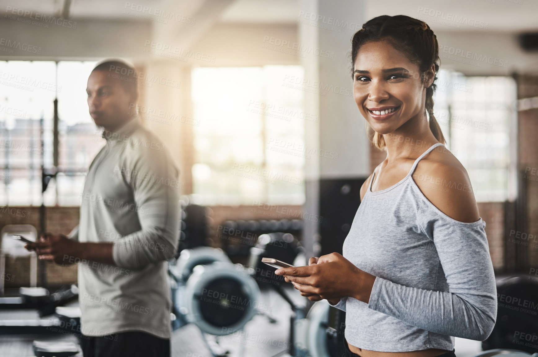 Buy stock photo Shot of a young woman using a mobile phone in a gym