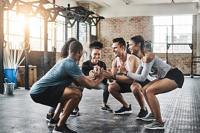 Buy stock photo Shot of a group of young people doing squats together during their workout in a gym