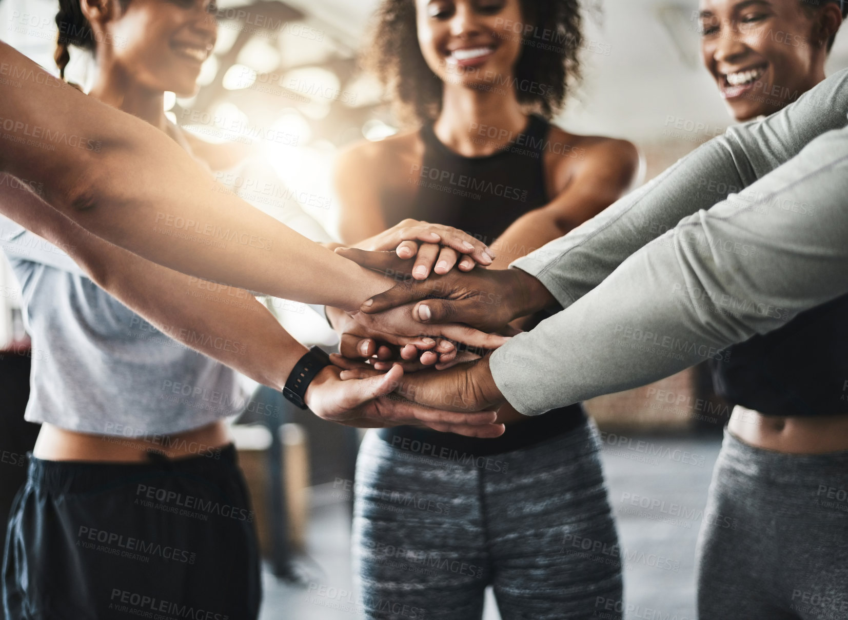 Buy stock photo Shot of a group of young people joining their hands together in solidarity at a gym