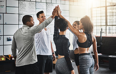 Buy stock photo Shot of a group of young people giving each other a high five during their workout in a gym